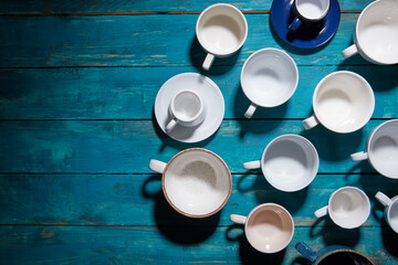 Empty colorful modern ceramic plates and bowls collection. Various of dishware over dark wooden background. Top view
