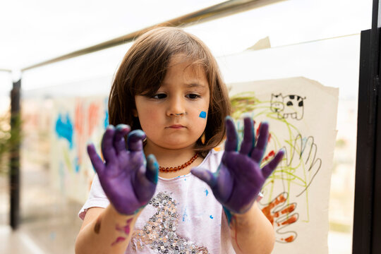Little girl messing around with her painted hands