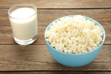 Cottage cheese for breakfast in bowl with milk on grey background.