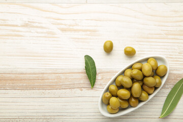 Fresh olives in bowl with leaves on white background with copy space.