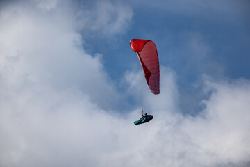 Paraglider is flying in the blue sky against the background of white clouds