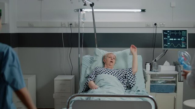 Sick woman asking for assistance from medical team in hospital ward bed. Doctor and nurse using oxygen tube and checking heart rate monitor for elder patient with respiratory problem.