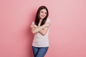 Photo of lovely attractive charming cheerful girl hugging herself comfort cozy isolated over pink pastel background