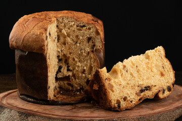 panettone with sliced traditional christmas food piece with black background.