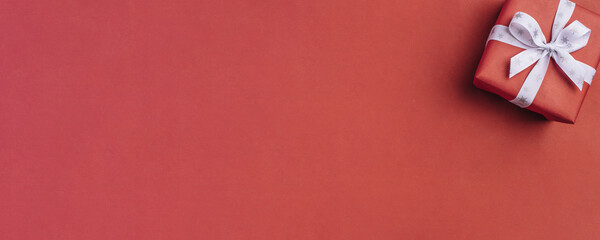 Gift boxe with white bow on a red backdrop.
