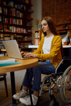 Disabled Female Student In Wheelchair Using Laptop