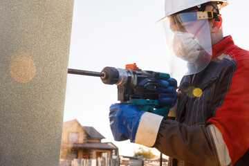 A male installer works with a hammer drill. Construction works.