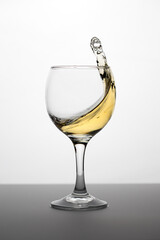 Wineglass with white wine with splash	