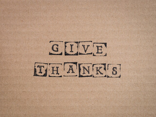 Cardboard with words Give Thanks made by black alphabet stamps.
