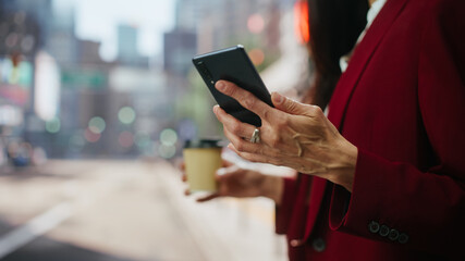 Close Up of Multiethnic Adult Businesswoman Using Smartphone on Street in a Big City. Confident Female Manager Connecting with People Online, Messaging, Browsing Internet on Her Way to Office.
