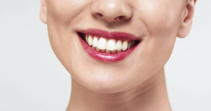 Close up of beautiful caucasian female model with gathered hair with straight white teeth smiling at camera.