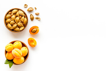Ripe apricots in bowl with apricot kernel, top view