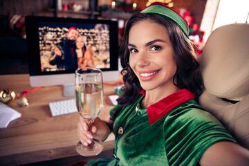 Photo of positive happy woman santa helper smile make selfie hold champagne talk online xmas indoors inside house home