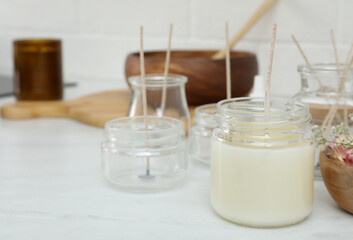 Glass jar with wax and wick on white table, space for text. Making homemade candle