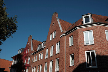 Rotbraune Klinkerfassaden mit typischem Giebel und weißen Fenstern vor blauem Himmel bei...