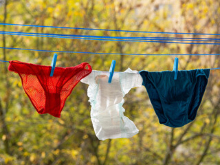 Baby diapers, women and man underwear hanging on a clothesline