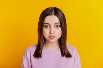 Photo of young girl pouted cheeks hold breath fooling grimace careree isolated over yellow color background