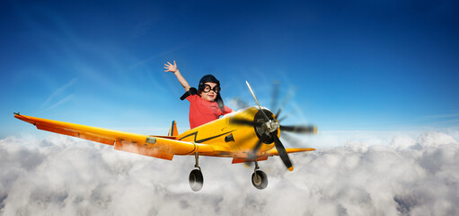 Naklejka na ściany i meble Boy flying riding a small yellow plane in the sky