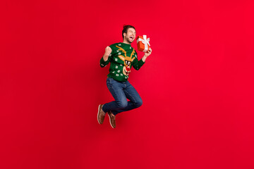 Full size photo of smiling crazy guy jumping scream happy receive new year present isolated on red color background