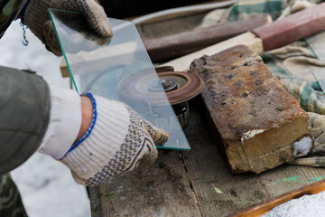 man polishes glass on grinding machine. Glass processing at home. Private business in rural...