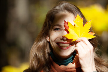 Young woman holding a maple leaf near her face