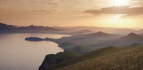 Beautiful sunset with rays over the contours of mountains with stones and sea. viewpoint between...