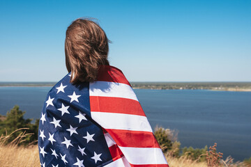 A young woman stands with an American flag wrapped around her against the backdrop of the bay. Free...