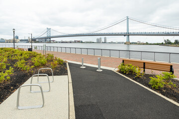 Walking path through the plants and grasses growing at RCA Pier Park on the Camden Waterfront, New Jersey, USA, with the Benjamin Franklin Bridge in the distance