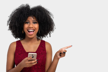 portrait of a beautiful black girl holding a cell phone and with her other hand pointing to the...