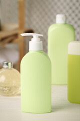 Bottles of shower gel on white wooden table in bathroom