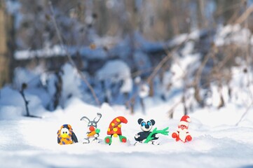 Figurines of fairy-tale characters in the winter forest. Santa Claus, a dwarf, a rabbit with a...