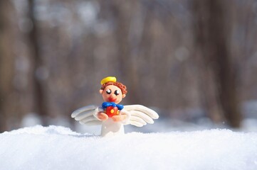 Christmas angel with a gift in the snowy forest.