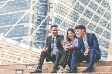 Young business team sitting on stairs and selfie with cityscape background.