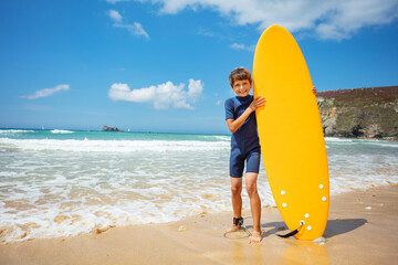 Boy pose holding orange surfboard stand in sea