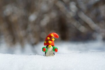 A figurine of a dwarf made of plasticine in a snowy forest. A fairy-tale character.