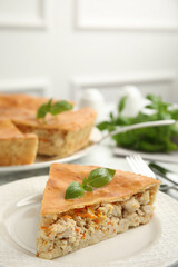 Piece of delicious pie with meat and basil in plate, closeup