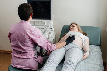 A pregnant girl gets an ultrasound of her abdomen at the clinic. Medical examination