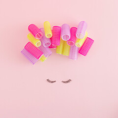 Creative arrangement made of eyelashes and colorful.curlers on a pastel pink background. Minimal...
