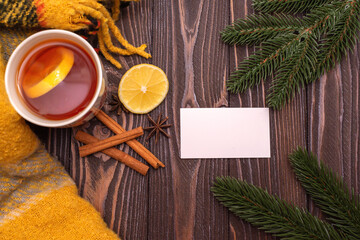 A cup of tea with lemon and cinnamon sticks on a wooden table, warm knitted snood. autumn mood