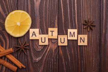 autumn from letters stands on a wooden background. Autumn word on blurry colorful autumn leaves background