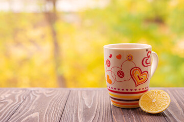 Cup with tea and lemon on a wooden surface with forest in the background
