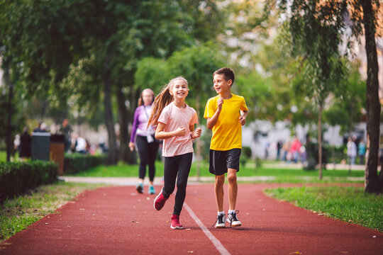 Child fitness, twins kids running on stadium track in city park , training and children sport healthy lifestyle. Outdoor activities by running make the child's body healthy and experience enriched