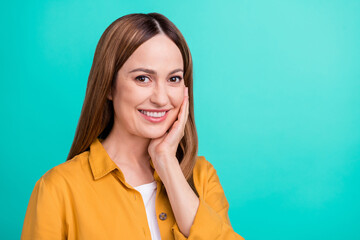 Photo of cute pretty mature lady wear yellow shirt arm cheek applying cream smiling isolated turquoise color background