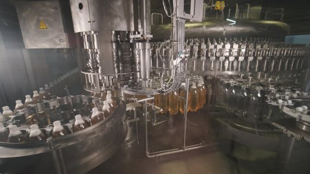 Automatic filling machine pours water into plastic PET bottles at modern beverage plant