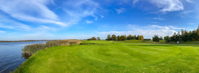 Panorama of sunny autumn landscape with beautiful meadow on the banks of Kisezers lake in Riga, Latvia.