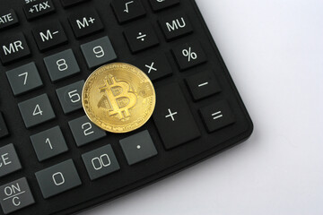 Bitcoin coin on a calculator on a white background with empty space.