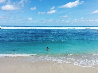 Fototapeta na wymiar Woman in tranquil blue waters on the beach under clear skies