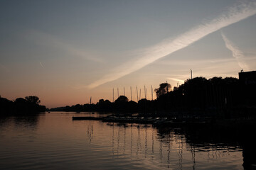 Sonnenuntergang im Herbst über dem Aasee mit Masten der Segelboote am Bootssteg in der Innenstadt...