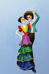 Dancing dia la Muertos couple - Ceramic decoration - against blue gradient background.