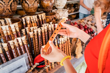 A female tourist inspects and tries to blow a duduk - a traditional Armenian musical wooden instrument at the handmade market in Yerevan © EdNurg